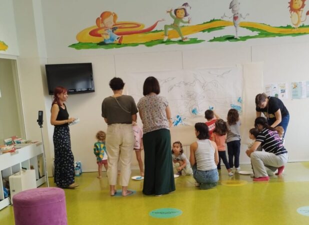 Infants pintant amb les mans el mural de La ola a la Biblioteca Mestre Martí Tauler de Rubí